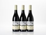 trois bouteilles de vin rouge sont posées sur une surface blanche