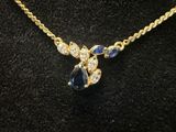 a gold necklace with blue and white stones on a mannequin