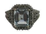 an image of a ring with an emerald stone surrounded by black diamonds