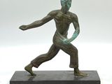 statue d'un homme en pose, posée sur un socle, avec un fond blanc