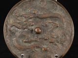 une plaque métallique ornée d'un motif, posée sur une surface noire