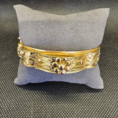 un gros plan d'un bracelet en or posé sur un oreiller