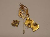 a gold brooch and a pair of earrings on a white surface