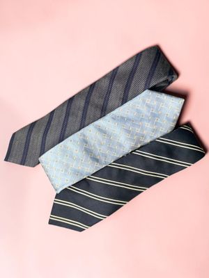 three ties are stacked on top of each other on a pink background