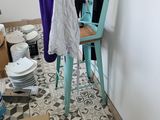 a room with a ladder, a chair, and a pile of plates on the floor