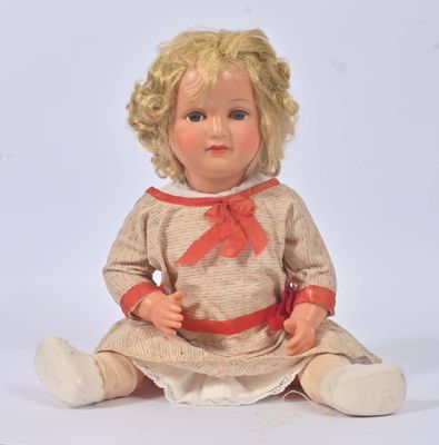 une poupée aux cheveux blonds, assise par terre