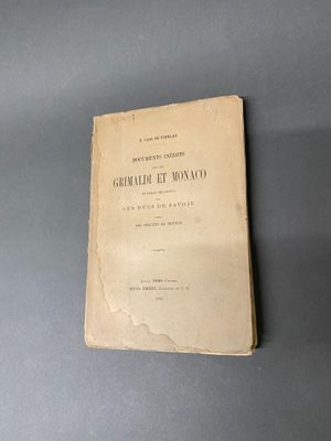 un vieux livre posé sur une table à côté d'un mur gris