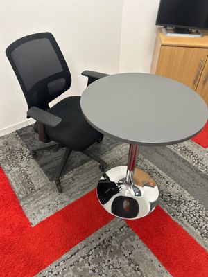 une chaise noire et une table grise dans un coin de la pièce
