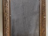 an old mirror is sitting on a shelf next to a white wall