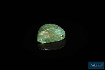 a close up of a green stone on a black surface