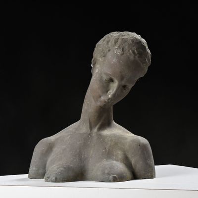 sculpture représentant un torse féminin sur un socle blanc, avec un fond noir