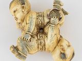 une figurine ancienne en ivoire représentant un garçon avec un oiseau sur le dos