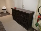 une commode noire dans une pièce équipée de toilettes et d'un lavabo