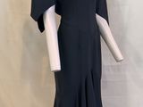 La robe est noire, avec un décolleté en V et une jupe évasée.