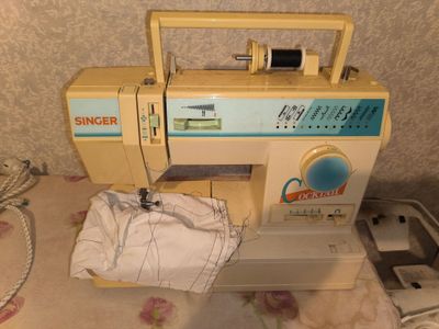 a sewing machine sitting on a bed next to a sewing machine
