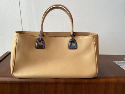 un sac à main beige et bleu posé sur une table en bois