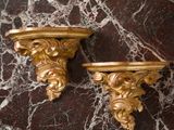 pair of antique gold leafed wall brackets on a marble surface