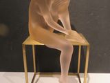 a glass sculpture of a nude woman sitting on a chair