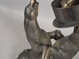 a silver statue of a dog holding a bowl and a bottle