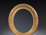 an oval mirror with a gold frame on a black background