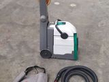 a vacuum that is sitting on the ground next to a hose