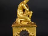 une image représentant une statue en or d'un homme assis au sommet d'une horloge