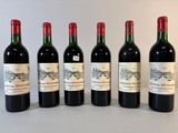six bouteilles de vin sont alignées sur une table