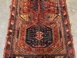 a red and black rug sitting on top of a cement floor