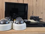 two cameras sitting on top of a desk next to a monitor