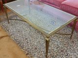 une table basse en verre posée sur un tapis, devant un canapé rose