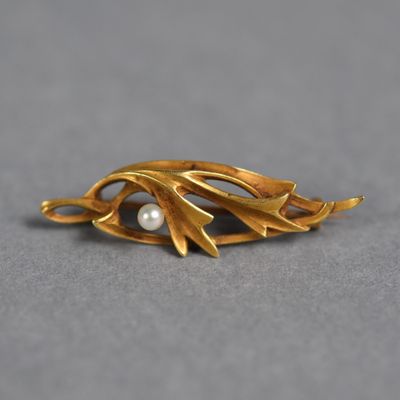 un gros plan d'une broche en or sertie d'une perle