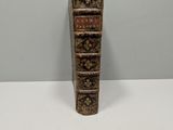 an old book with a candle on top of it sitting on a table