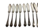 six silverplated knives are lined up next to each other on a white surface