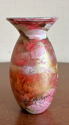 un vase rose et doré posé sur une table en bois