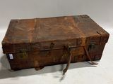 une vieille valise posée sur une surface blanche