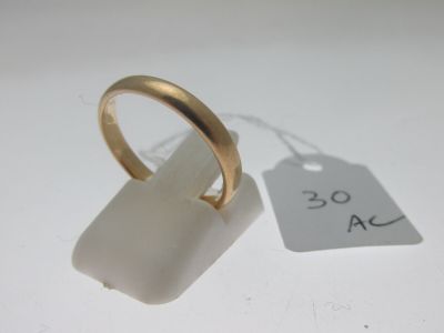 une bague en or posée à côté d'une étiquette sur une surface blanche