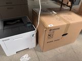une imprimante posée à côté d'un carton posé par terre