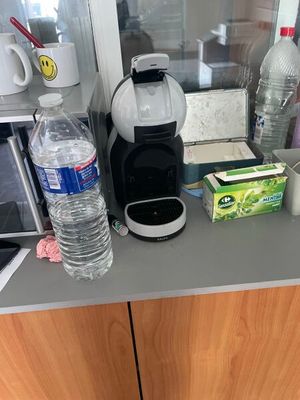 une cafetière posée sur le plan de travail de la cuisine, à côté d'un verre d'eau