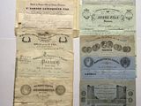 several old paper certificates are displayed on a white surface