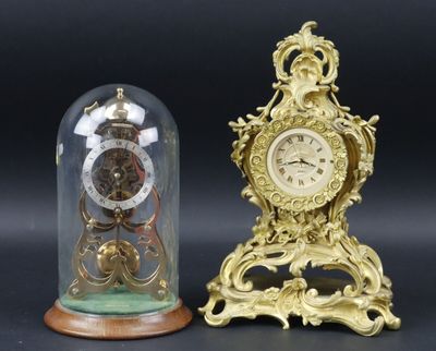 deux horloges posées sur une table, sous un dôme en verre