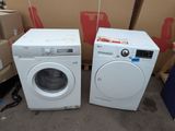 pair of white washing machines sitting next to each other in front of boxes