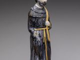 une statue représentant un homme vêtu d'une robe noire et tenant un ruban jaune