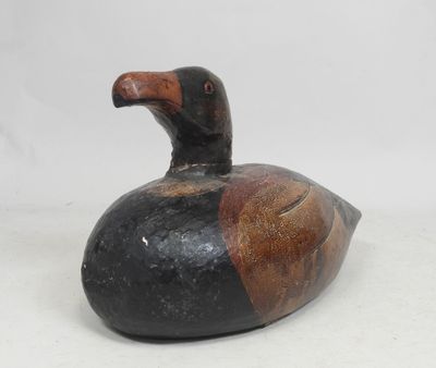 an image of a black and brown duck sitting on top of a white surface