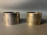 two silver napkins with a design on them on a table