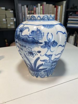 a blue and white vase sitting on a table in front of a bookshelf