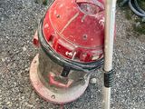 a red and white vacuum on the ground with a baseball bat in it