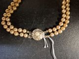 a close up of a necklace with pearls and a silver clasp
