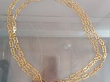 a gold necklace with a cross on it in a display case