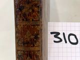 un vieux livre posé à côté d'un bout de papier sur lequel il y a quelque chose d'écrit