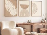 un salon avec un fauteuil, une table et deux tableaux accrochés au mur